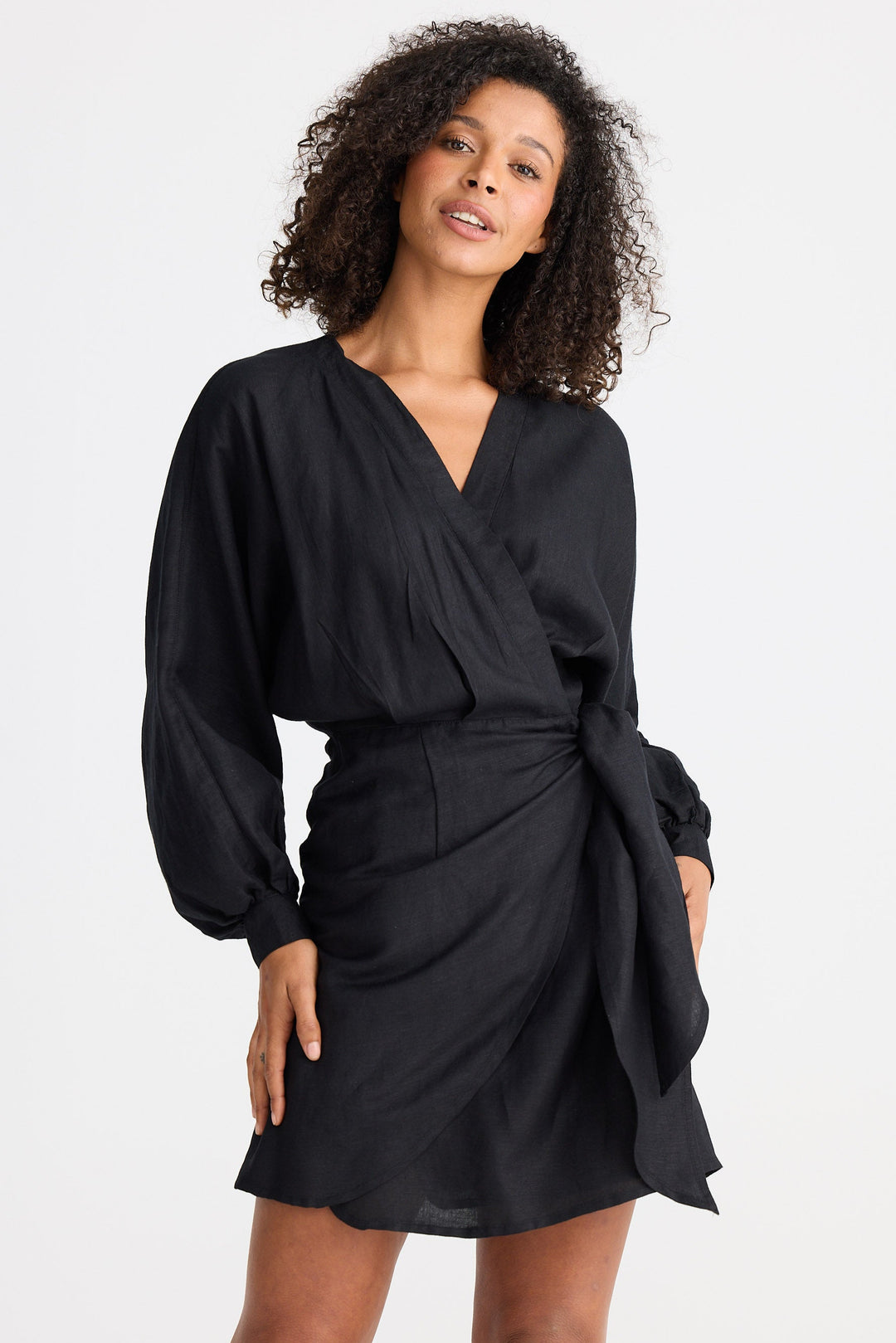 Woman wearing a black wrap dress against a white background