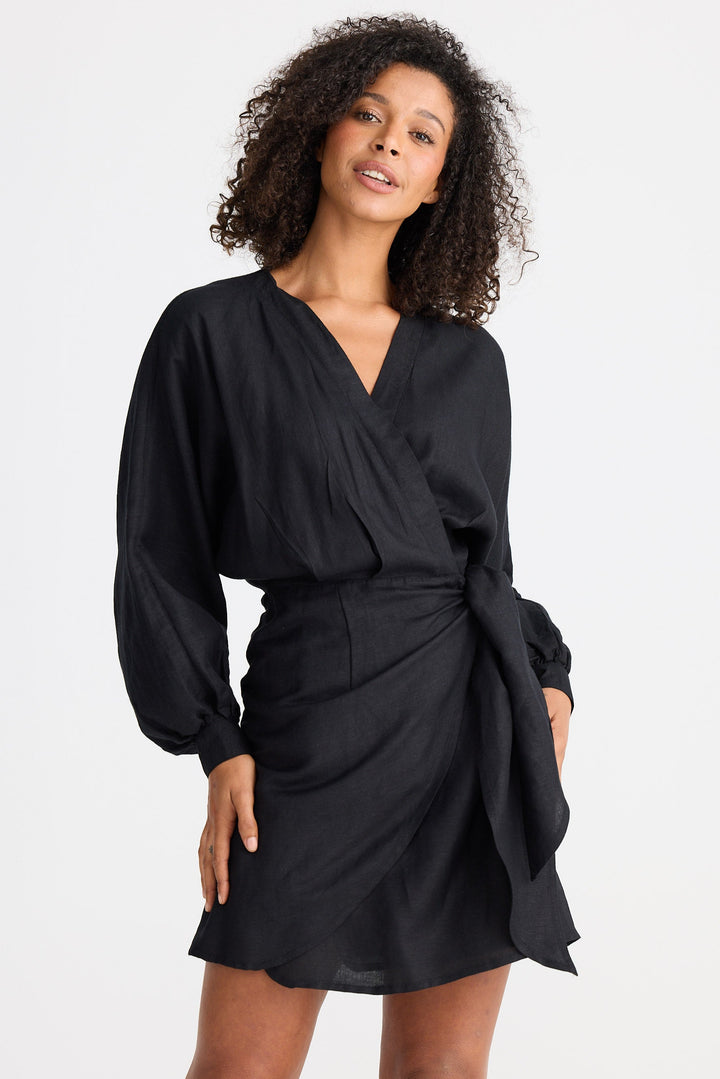 Woman wearing a black wrap dress against a white background