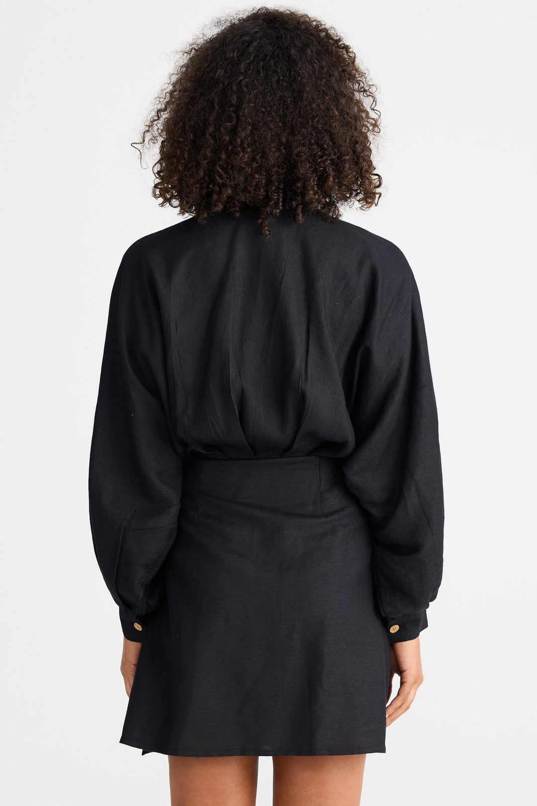 Person wearing a black wrap dress on a white background
