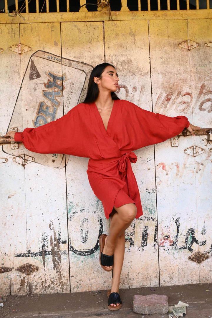 Person in a red dress leaning on a textured door with faded paint