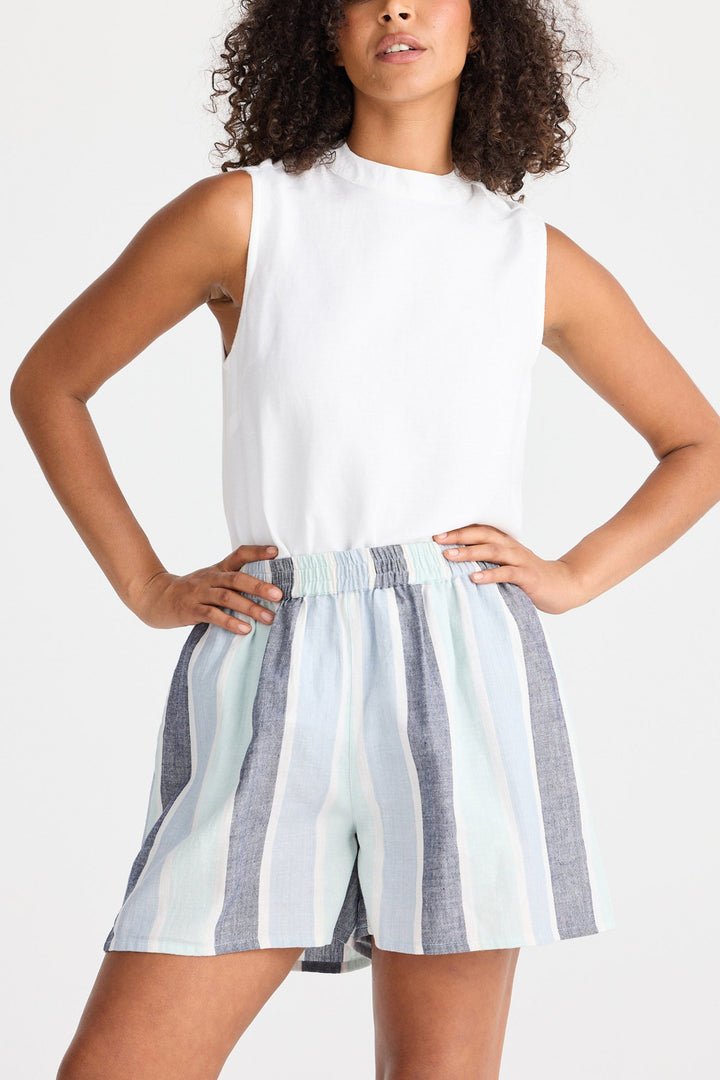 Woman wearing a white sleeveless top and striped shorts on a white background