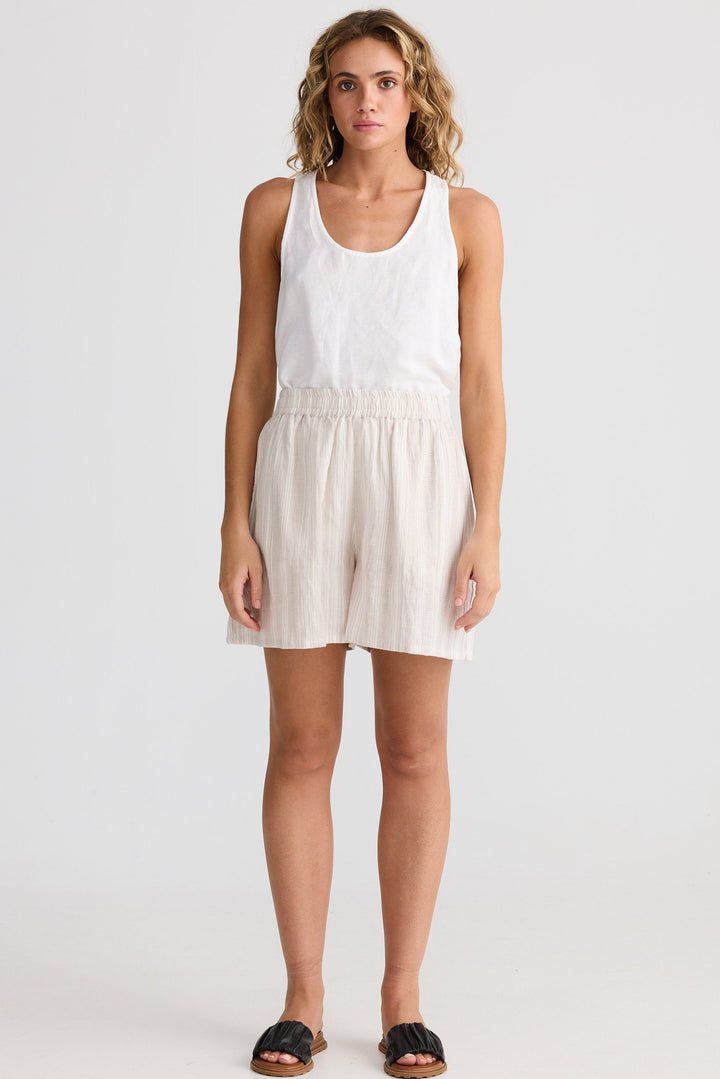 Woman wearing a white tank top and beige shorts on a white background