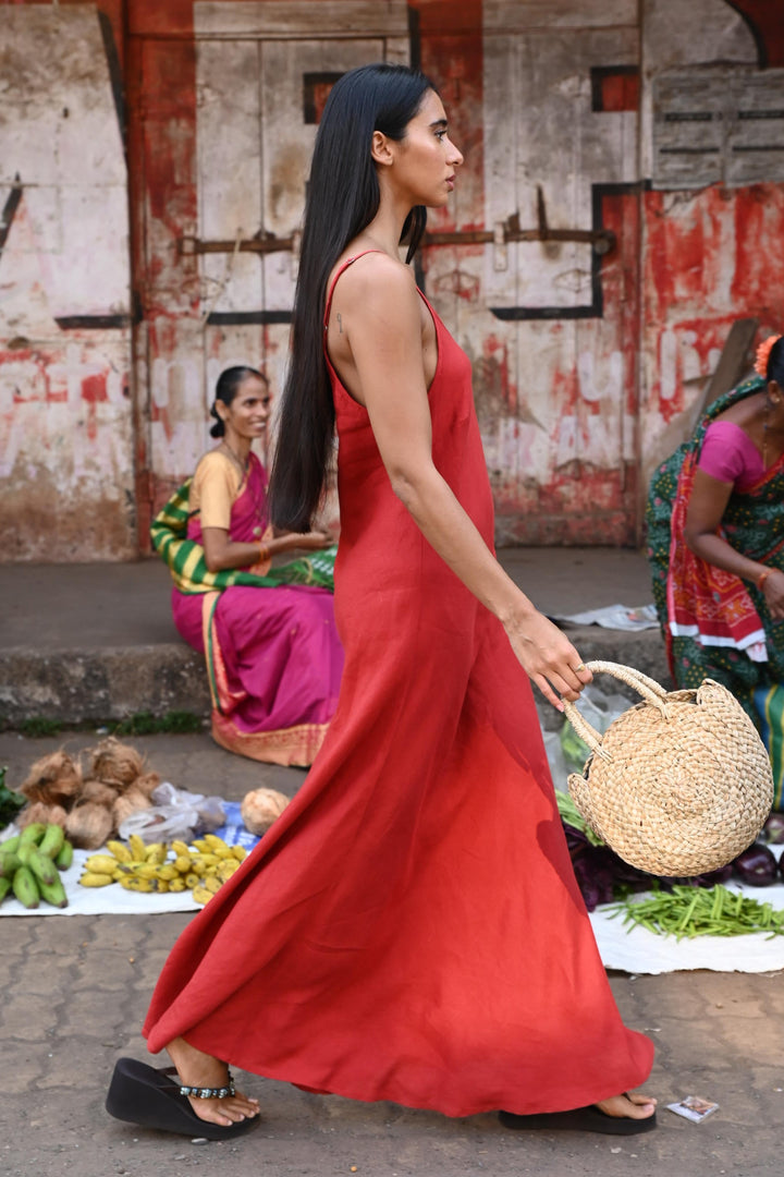 Woman in a red dress walking through an outdoor market.