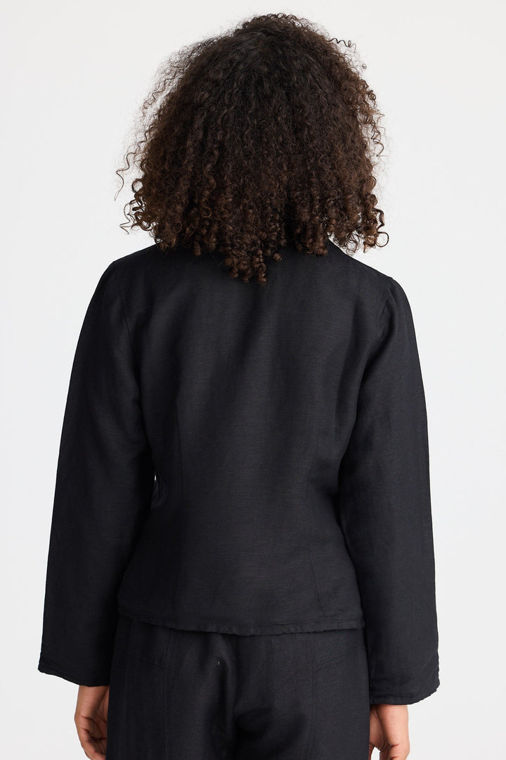 Person wearing a black jacket and pants with a plain background