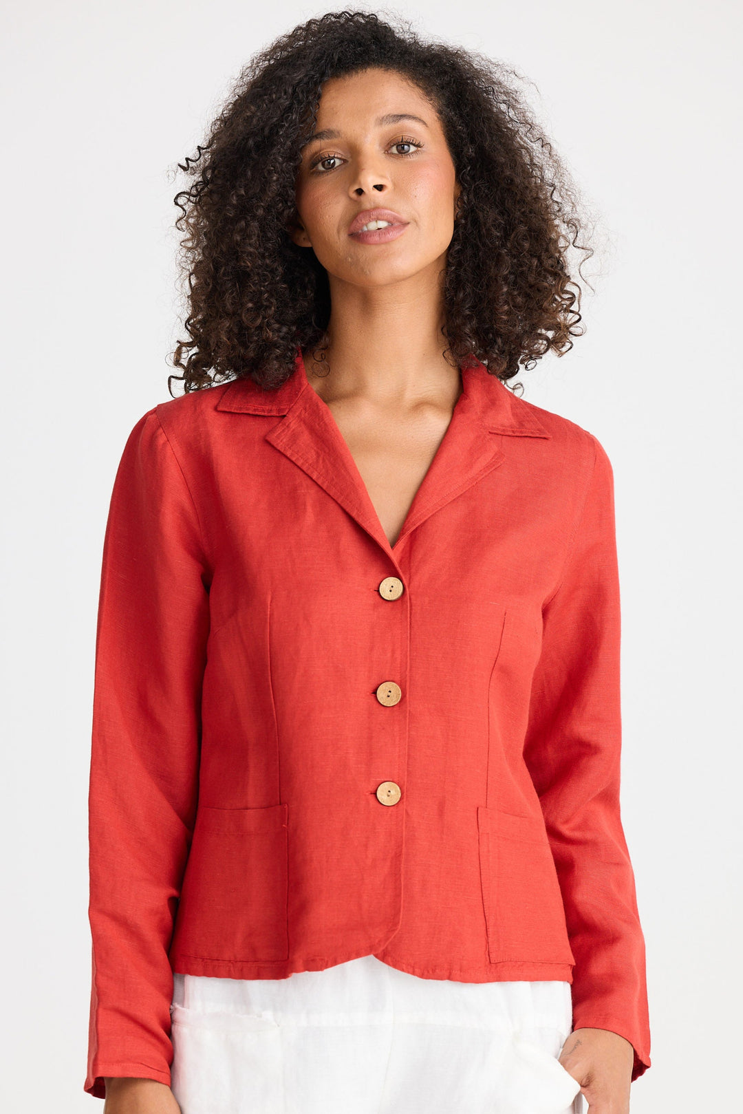 Woman wearing a red jacket with wooden buttons on a white background
