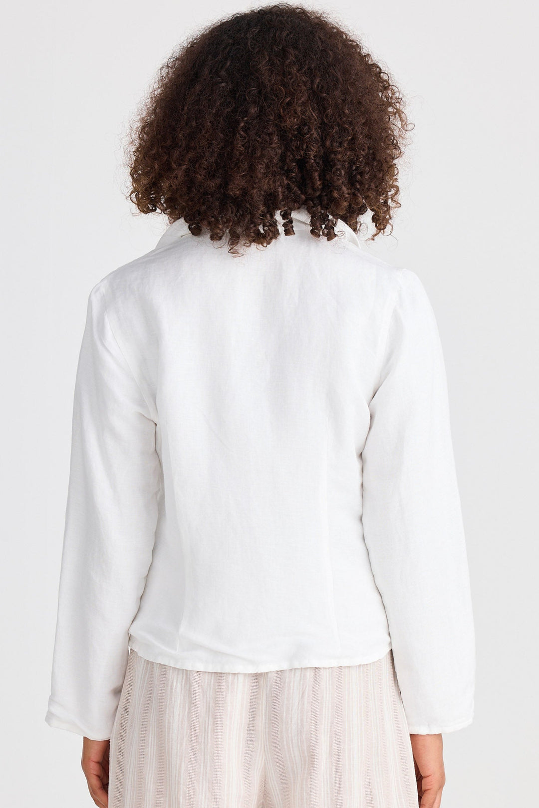Person wearing a white jacket and beige shorts on a plain background