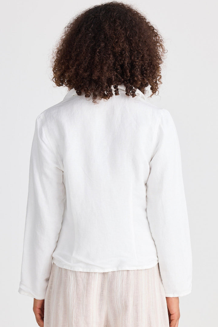 Person wearing a white jacket and beige shorts on a plain background