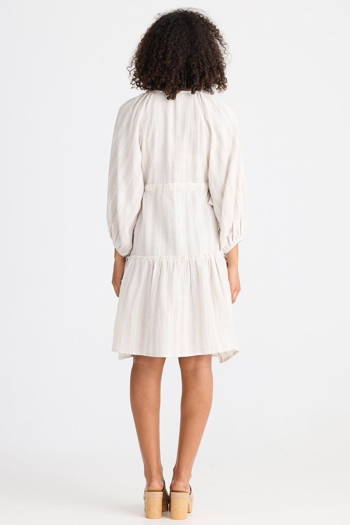 Woman wearing a light dress with a plain background