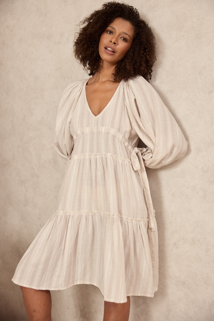 Woman wearing a light dress against a neutral background
