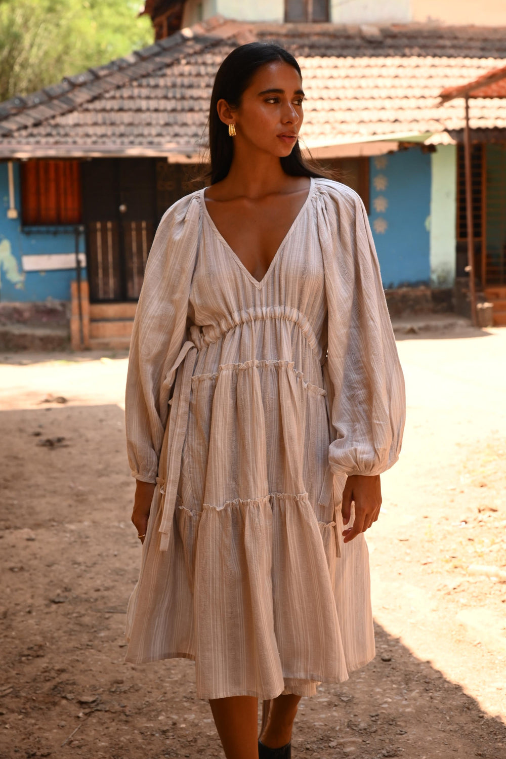 Woman wearing a light-colored dress standing outdoors with a blurred background