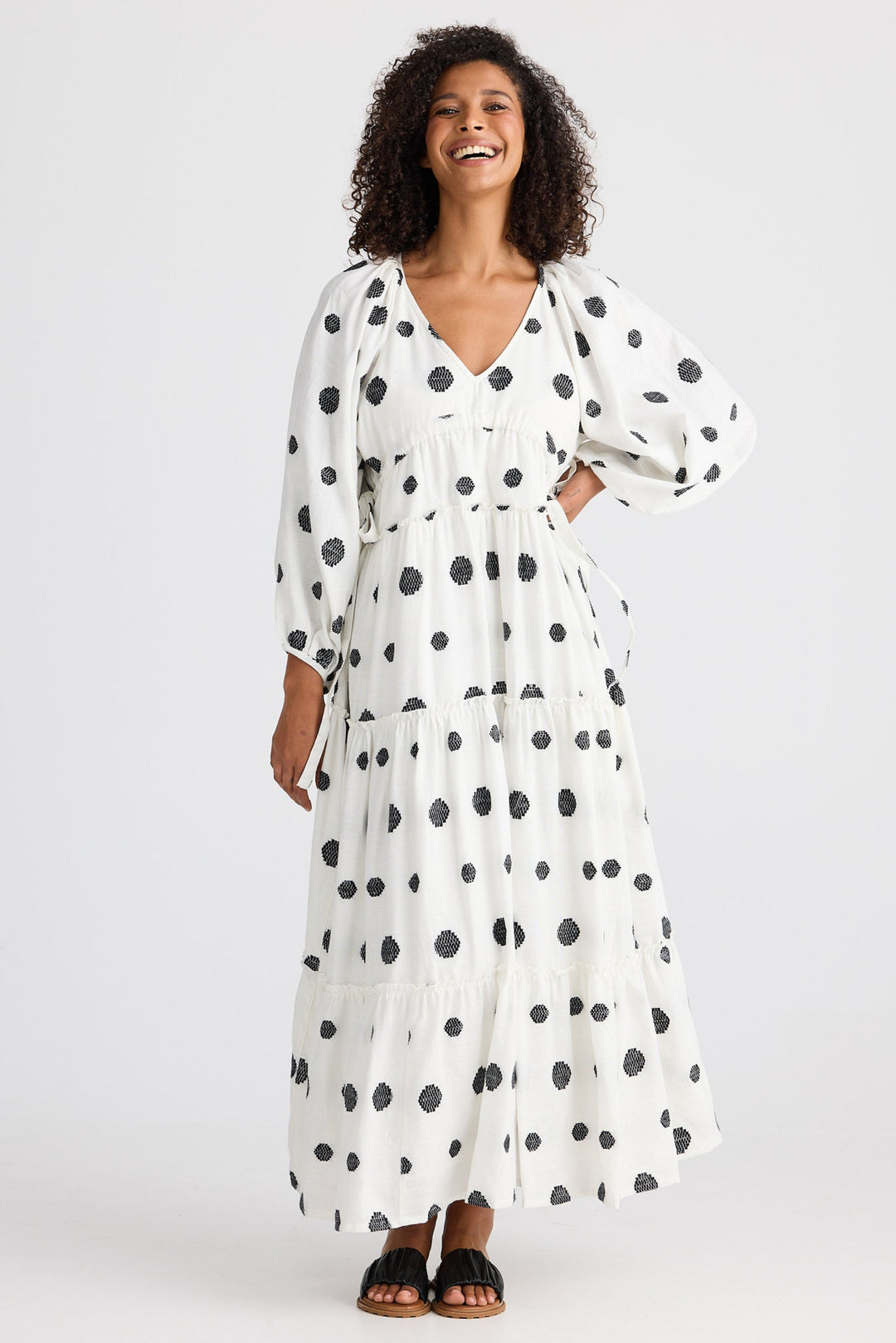 Woman wearing a white dress with black polka dots on a white background