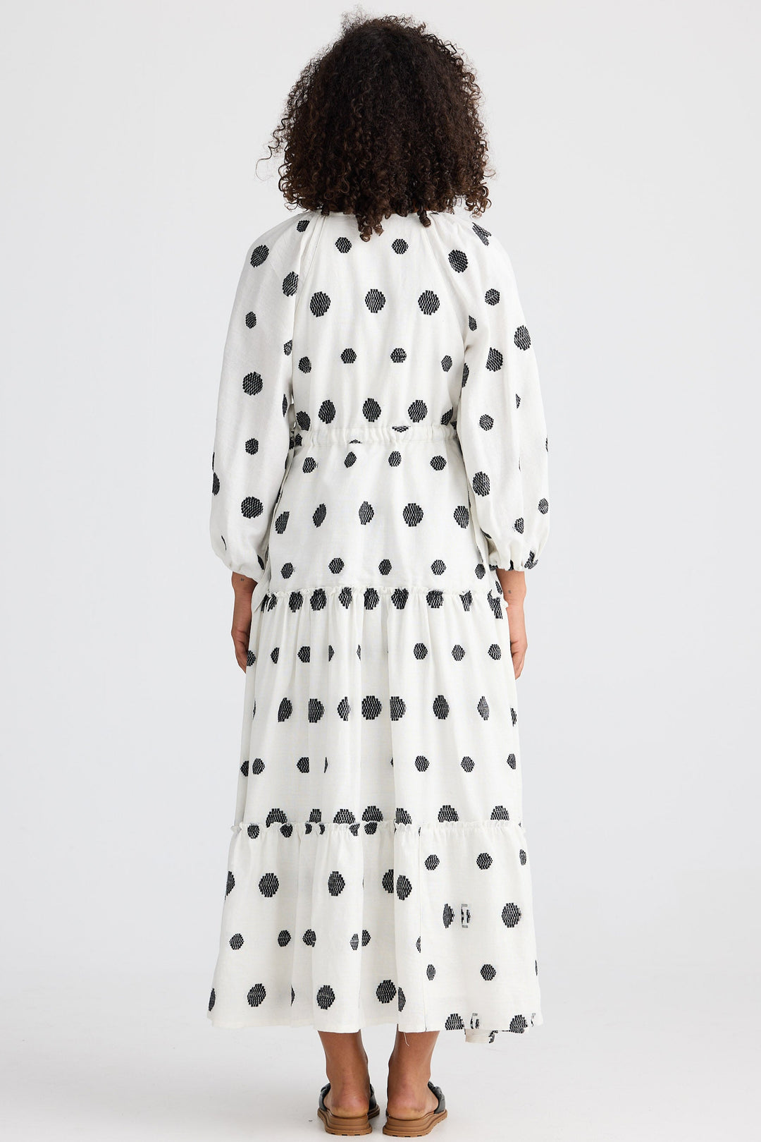 Woman wearing a long polka dot dress on a white background