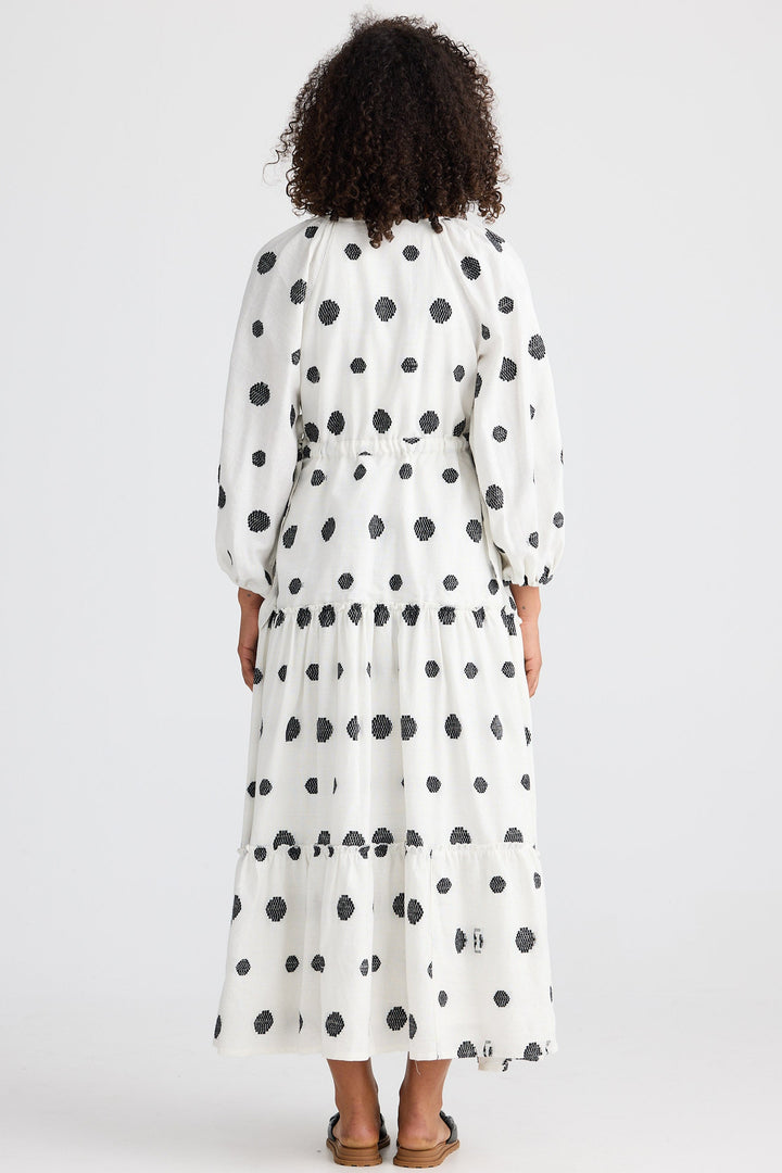 Woman wearing a long polka dot dress on a white background