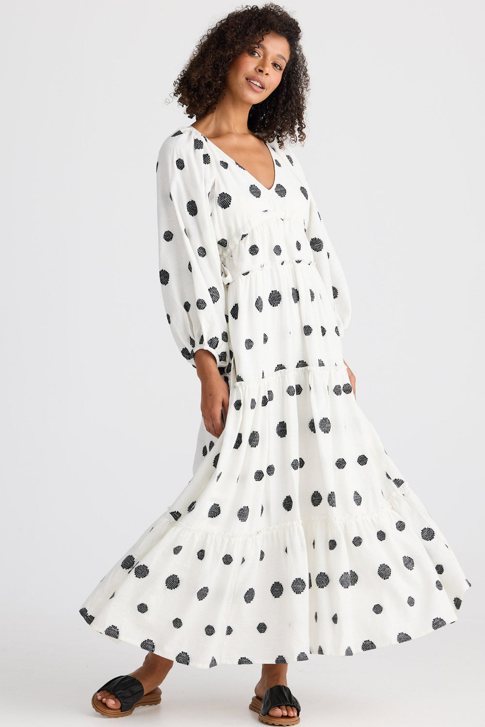 Woman wearing a white dress with black polka dots on a white background