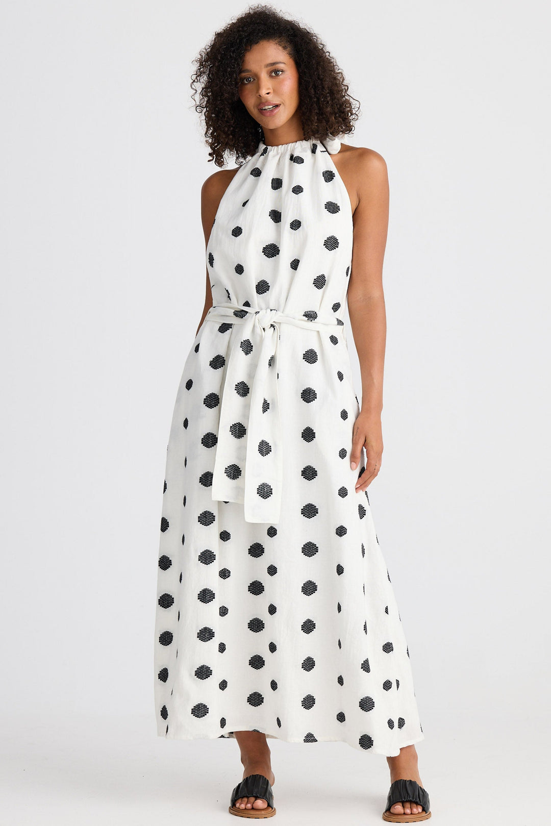 Woman wearing a white dress with black polka dots on a white background