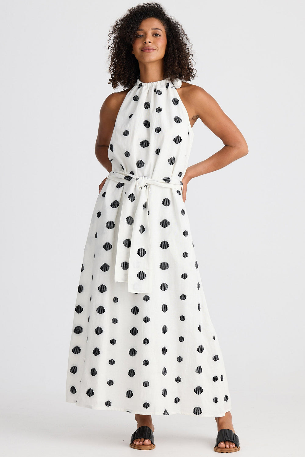 Woman wearing a white dress with black polka dots on a white background