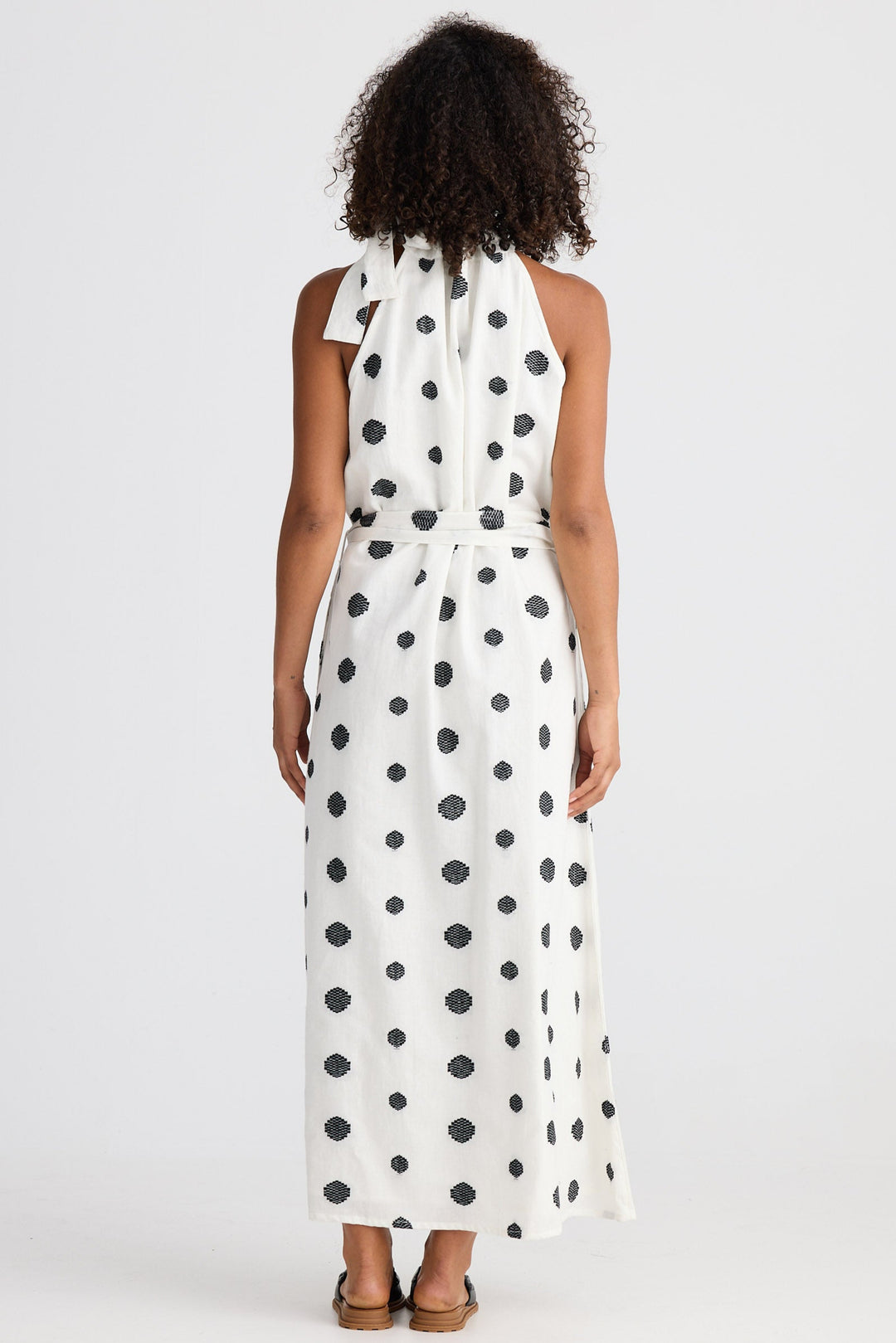 Woman wearing a white dress with black polka dots on a white background