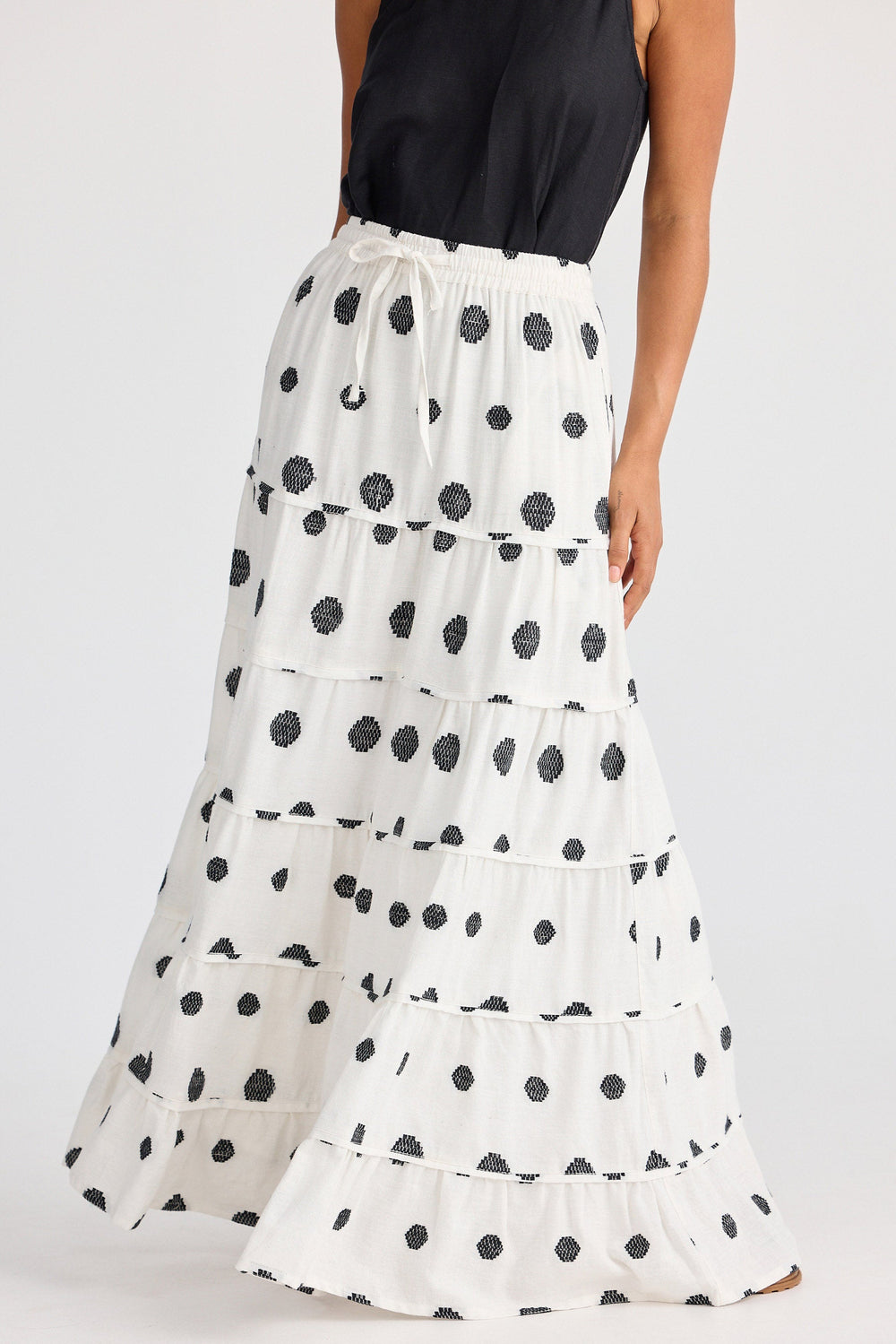 White tiered skirt with black polka dots worn by a person on a white background