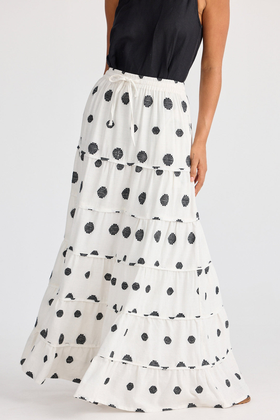 White tiered skirt with black polka dots worn by a person on a white background