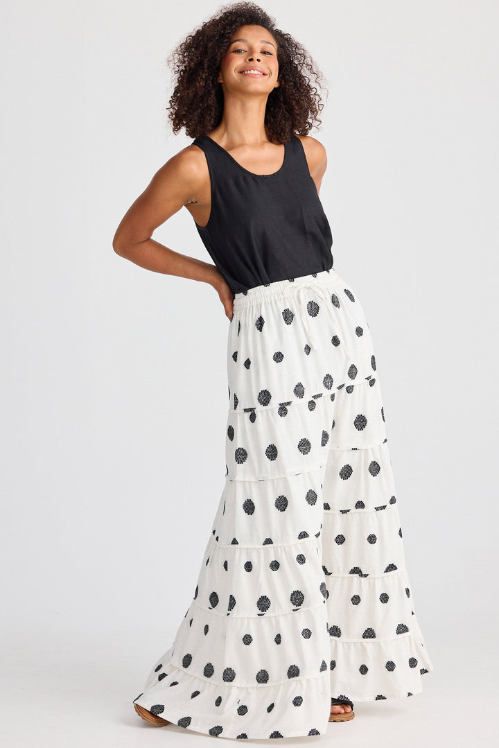 Woman wearing a black sleeveless top and white polka dot skirt on a light gray background