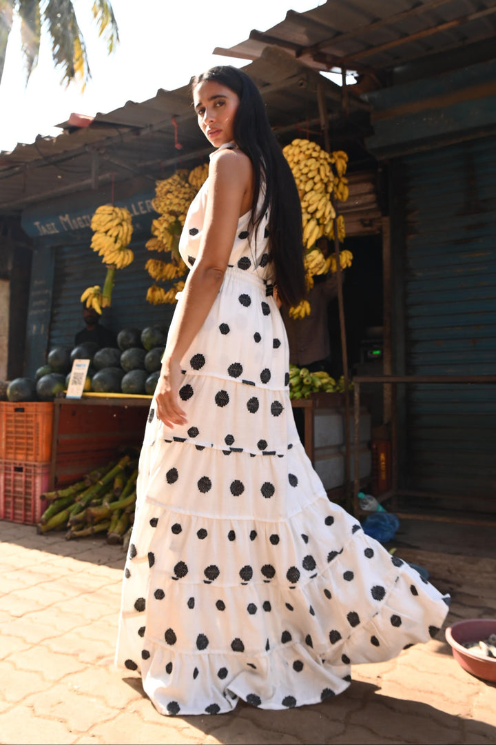Woman in a polka dot top and skirt walking through a fruit market.