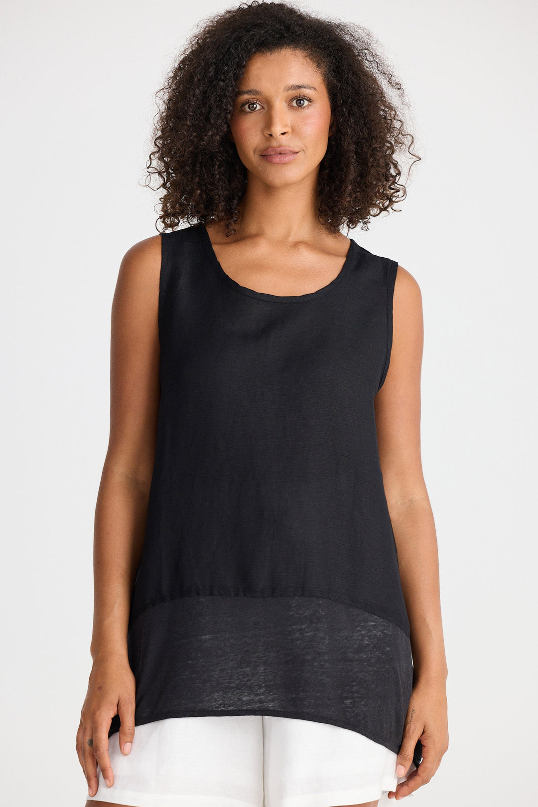 Woman wearing a black sleeveless top and white shorts on a white background