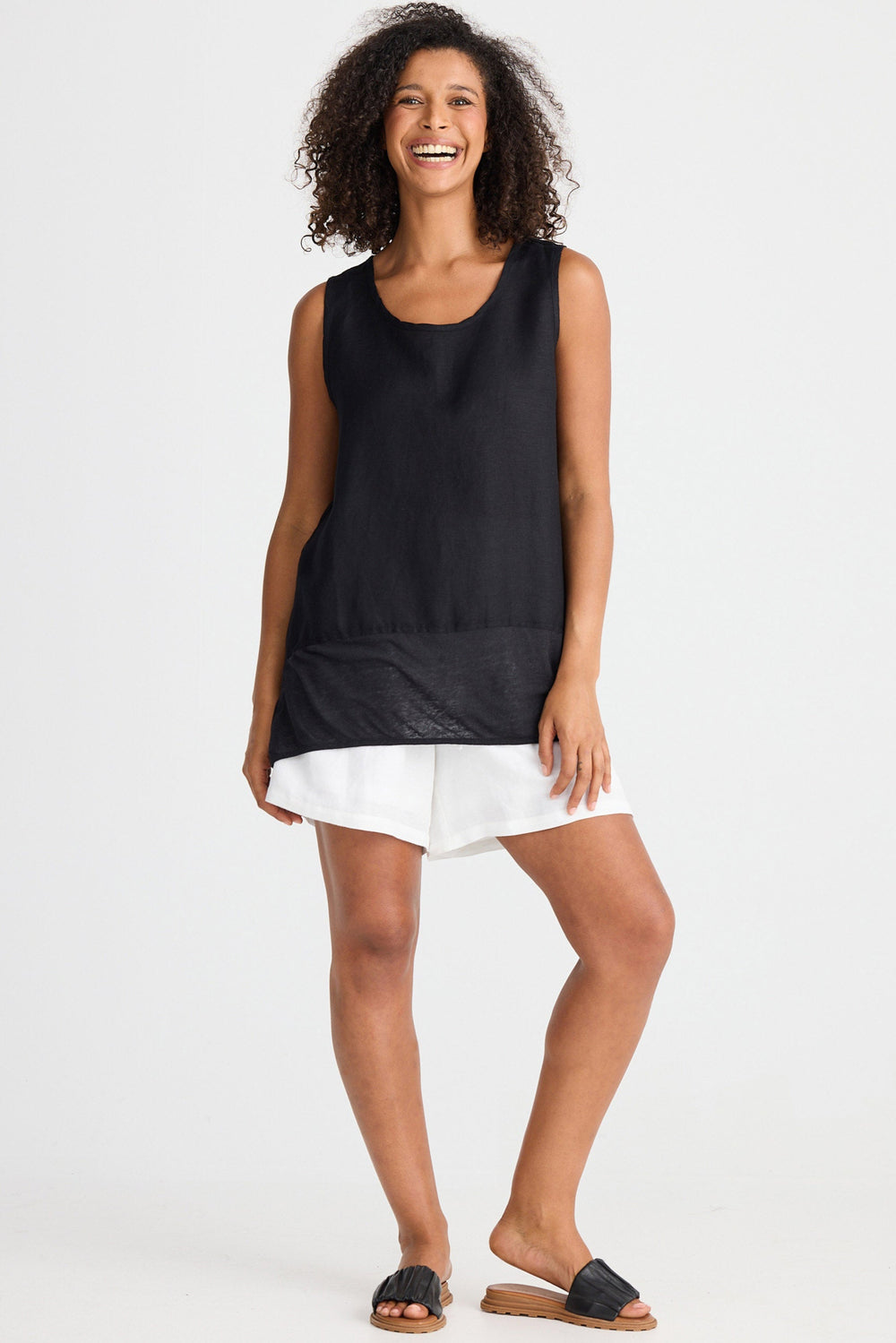 Woman wearing a black sleeveless top and white shorts on a white background