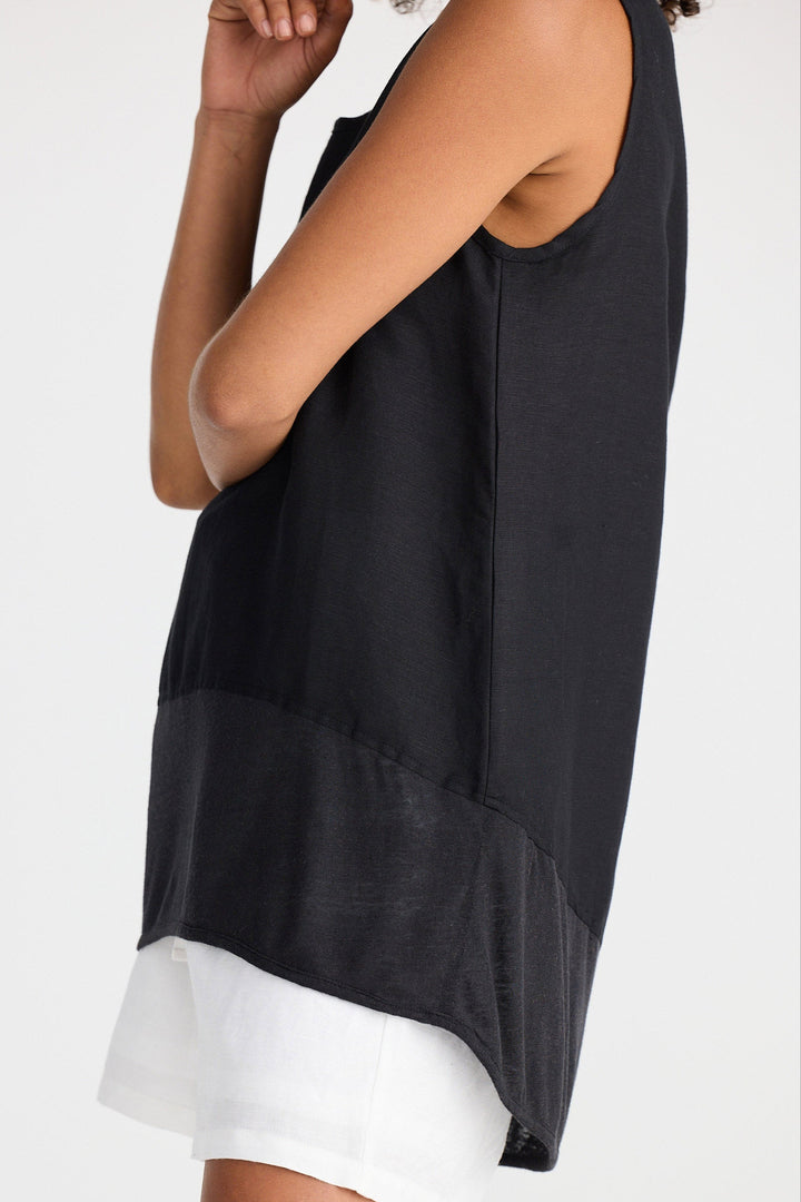 Black sleeveless top with white trim worn by a person on a white background