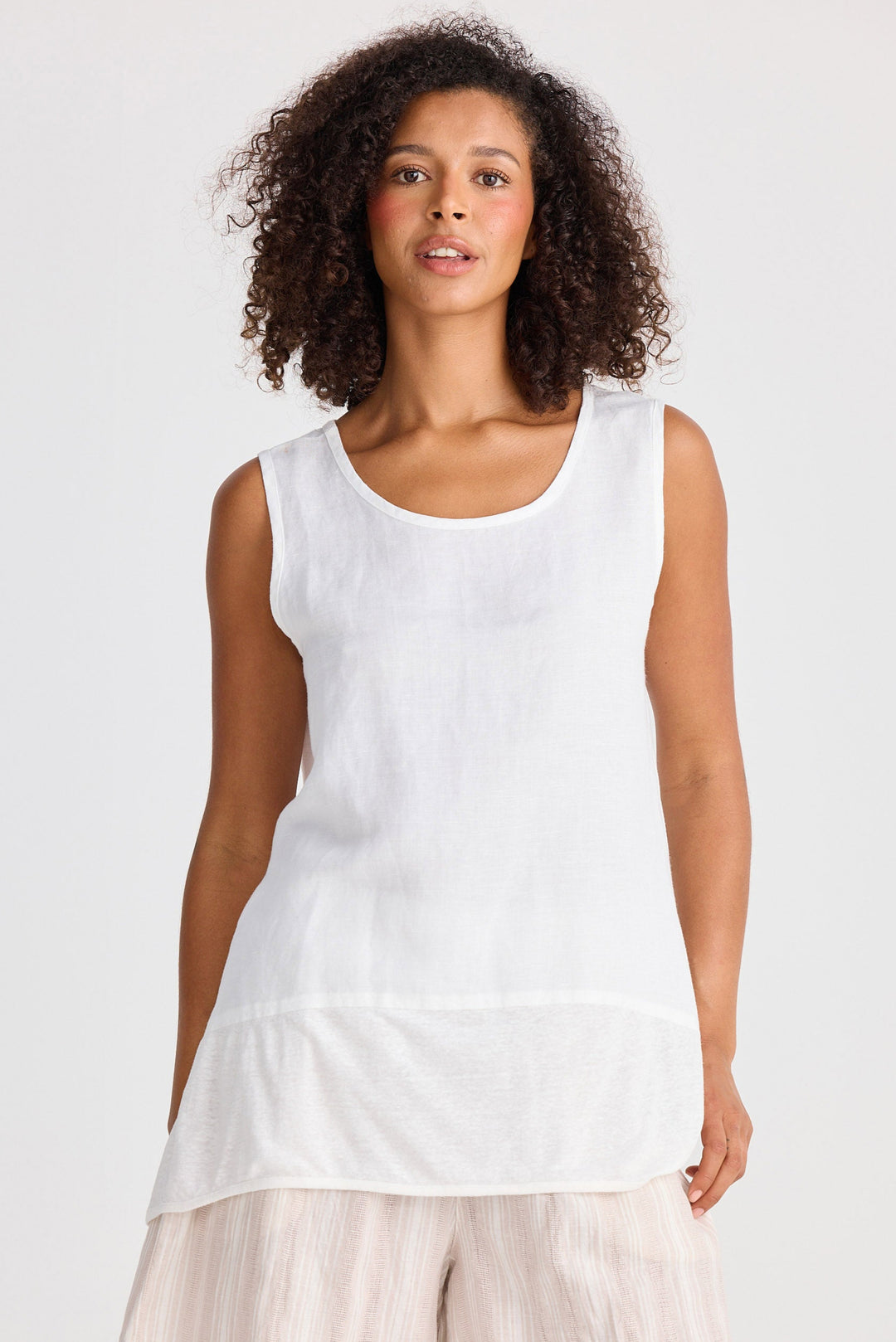 Woman wearing a white sleeveless top and beige shorts on a white background