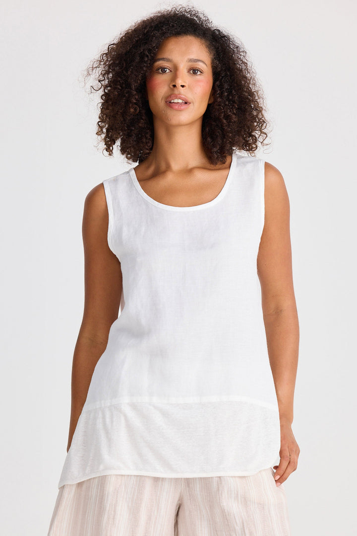 Woman wearing a white sleeveless top and beige shorts on a white background