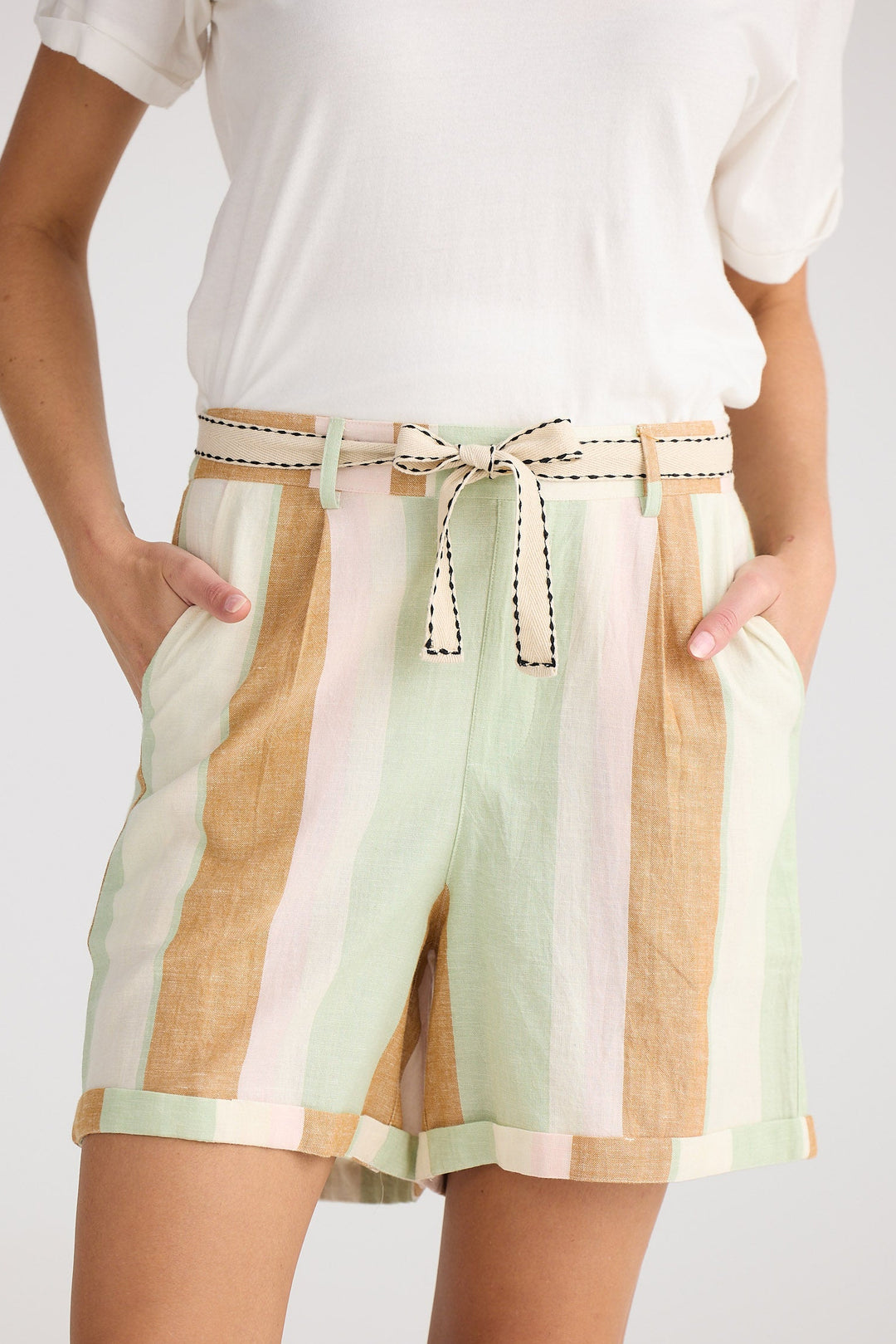 Person wearing a white top and colorful striped shorts on a plain background
