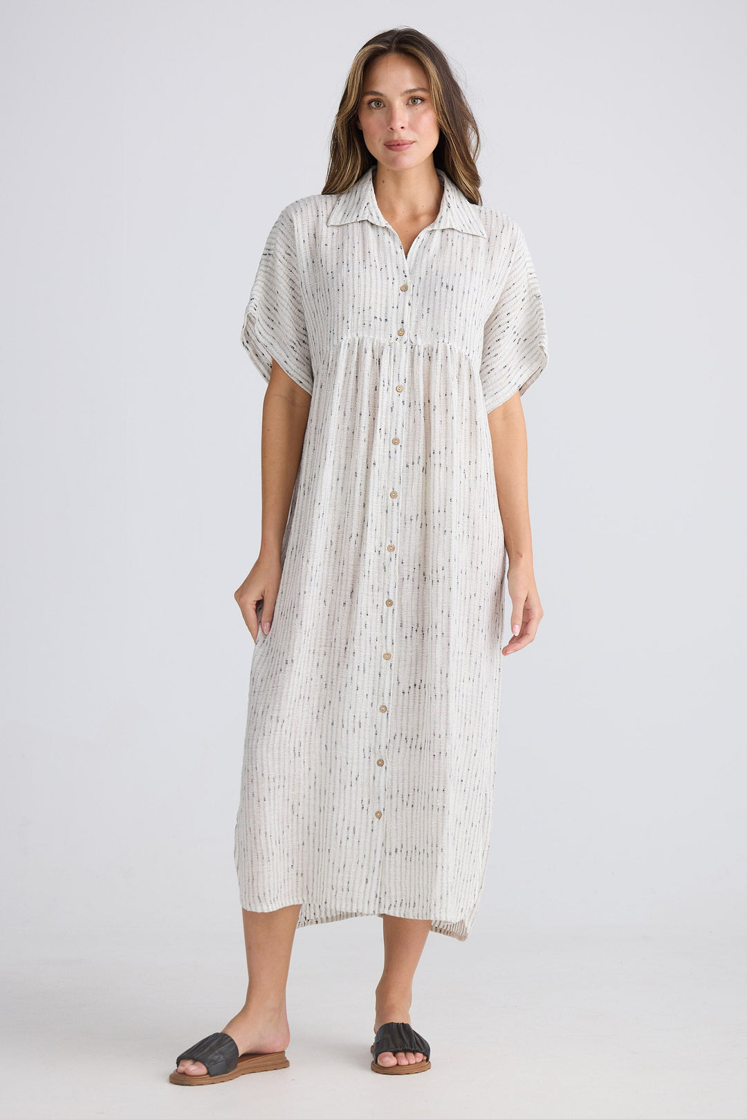 Woman wearing a white patterned dress on a plain background