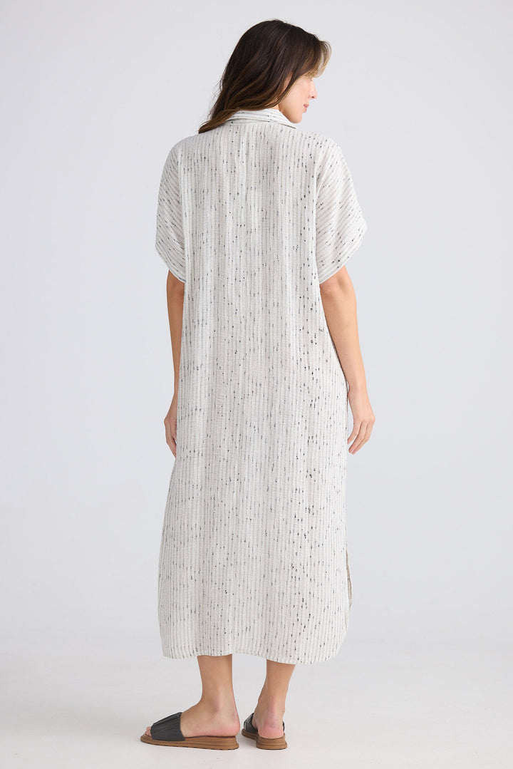 Woman wearing a white patterned dress on a plain background