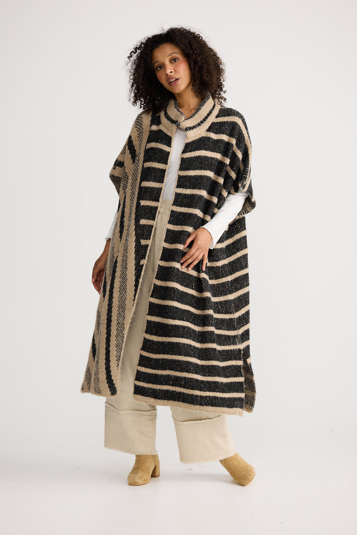 Model wearing black w cedar stripe Mirador Knit Cape, side view on white background