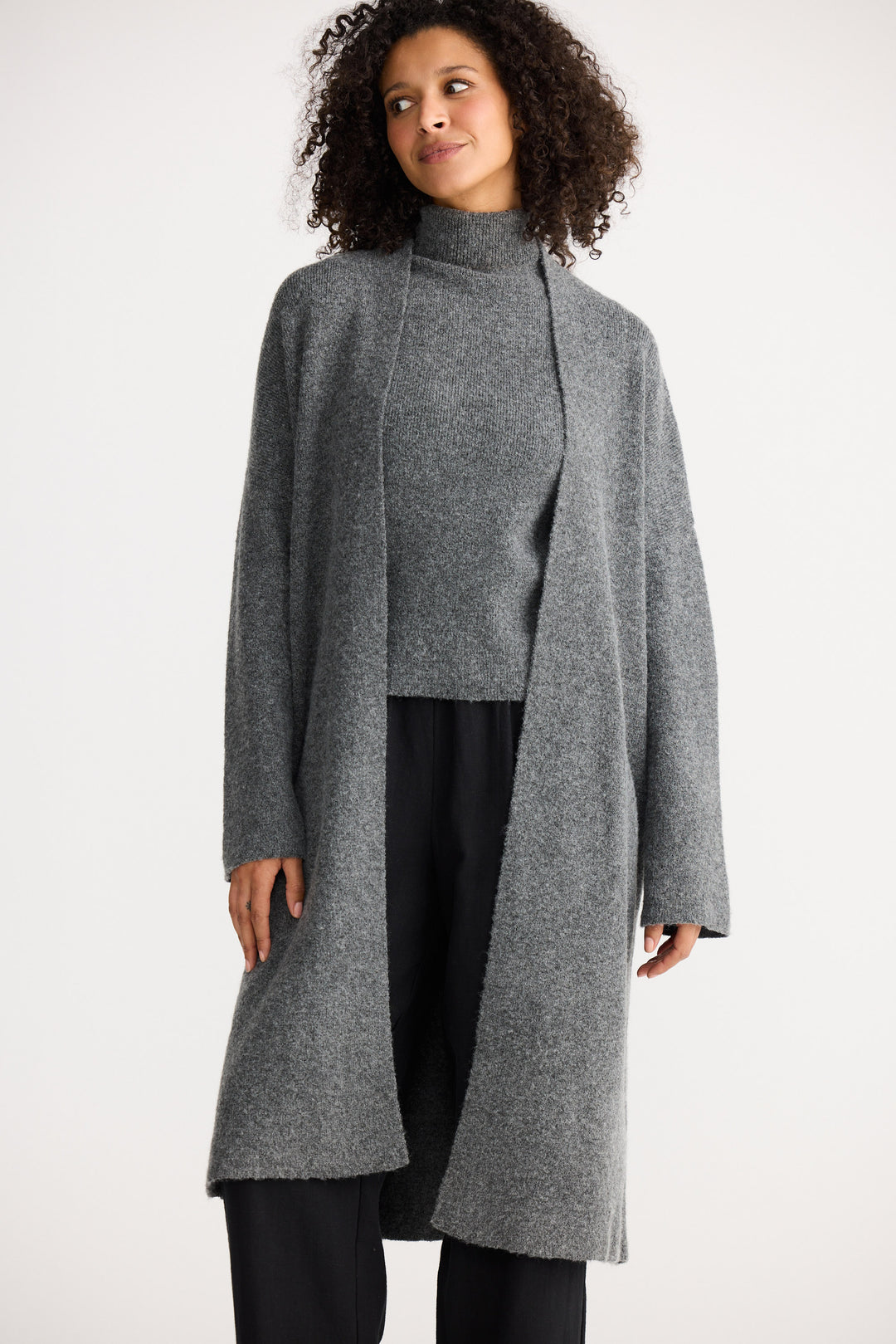 Woman wearing a gray coat over a gray sweater on a white background