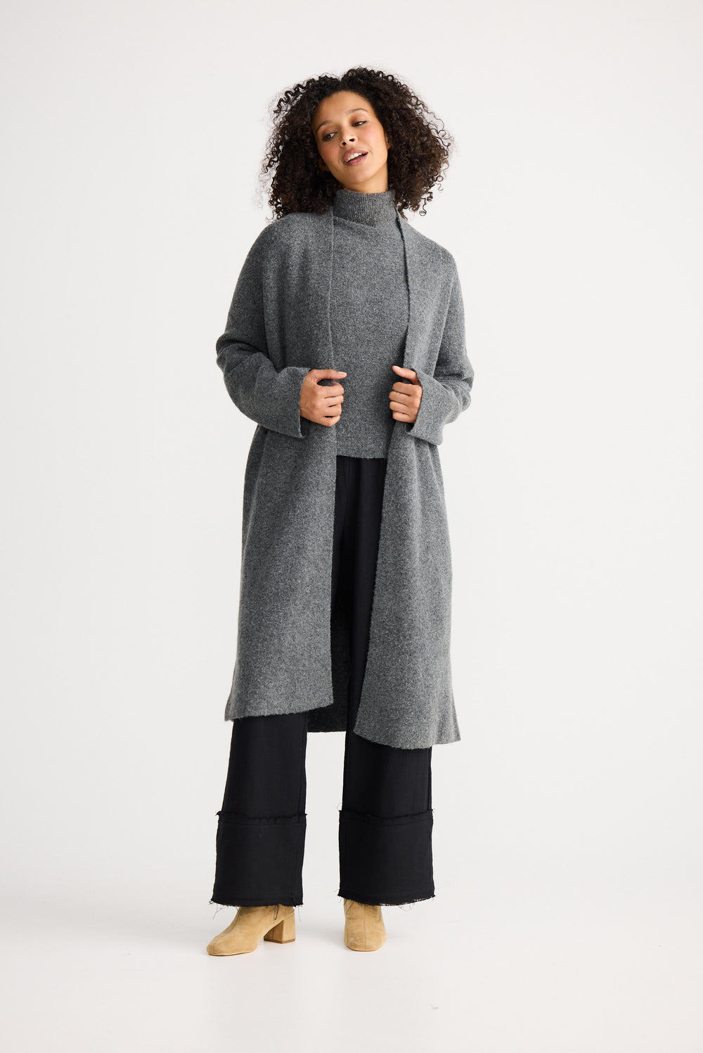 Woman wearing a gray long cardigan over a black outfit on a white background