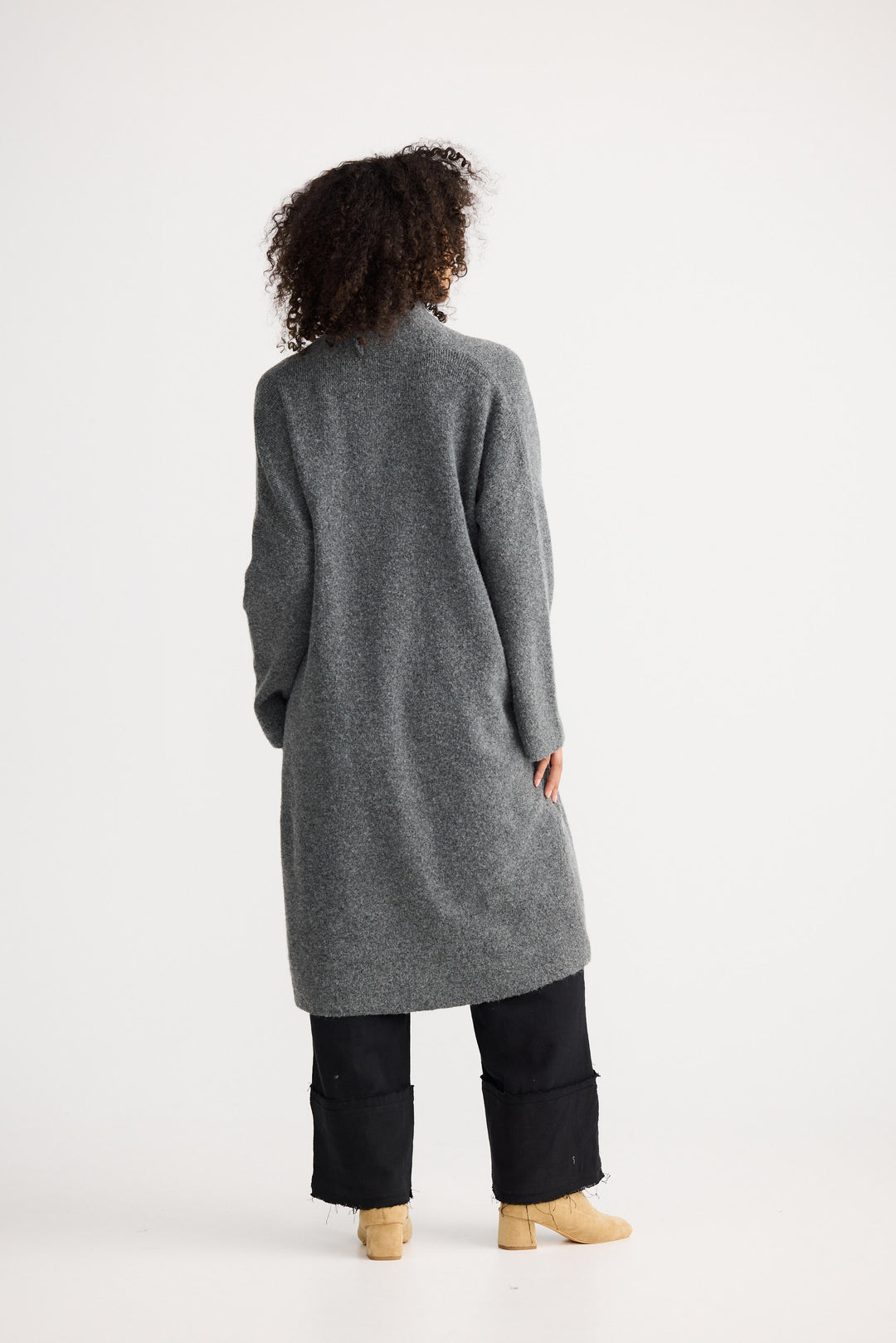 Person wearing a long gray cardigan on a white background
