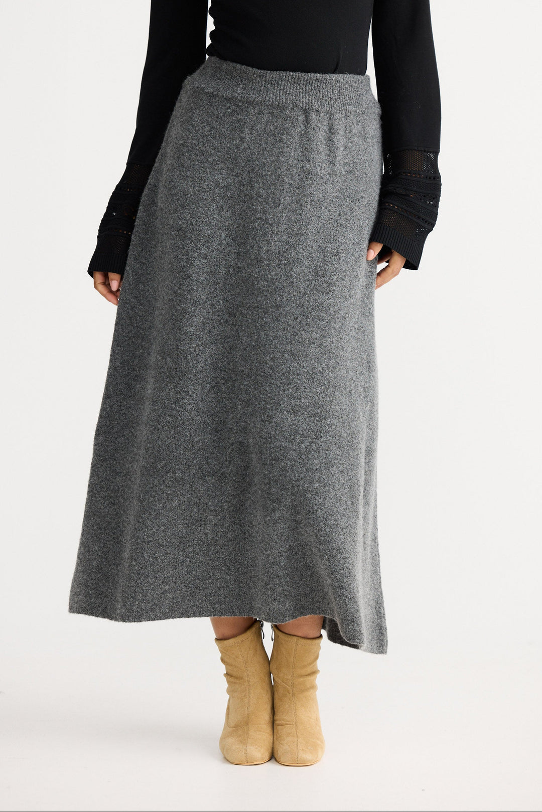 Person wearing a gray skirt with a black top on a white background
