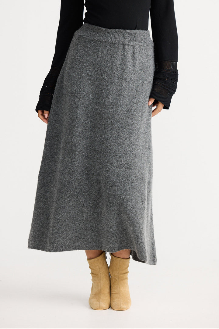 Person wearing a gray skirt with a black top on a white background