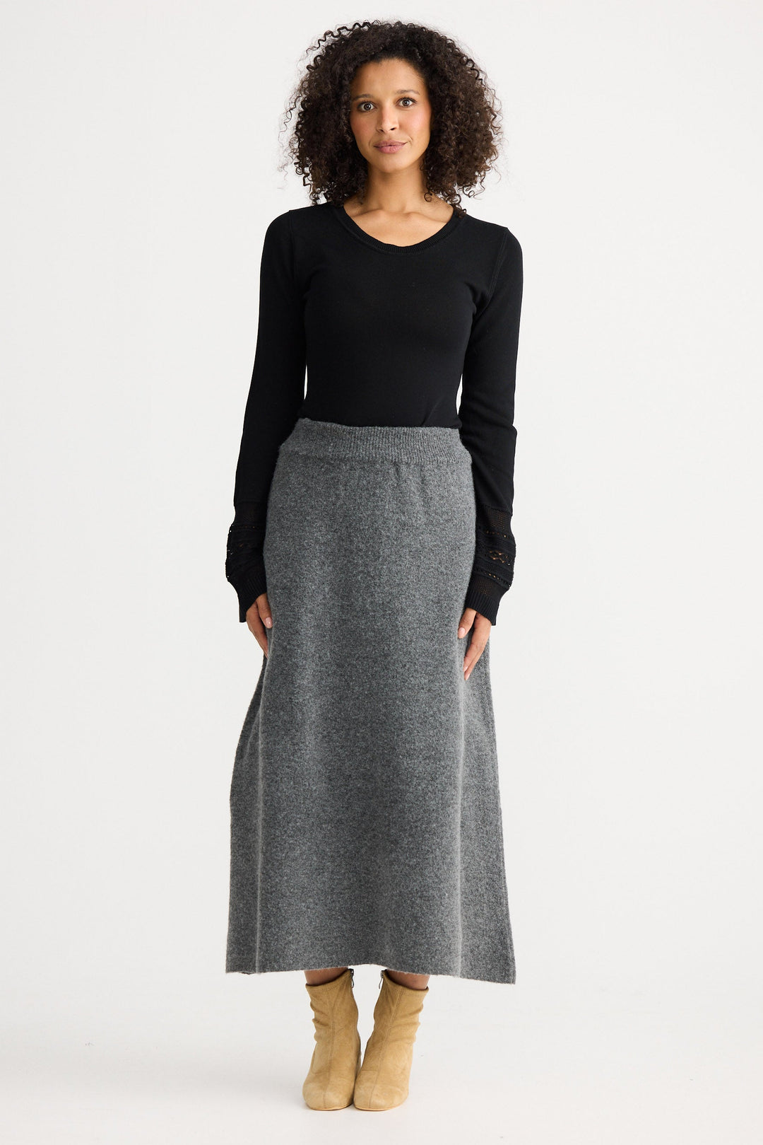 Woman wearing a black top and gray skirt on a white background