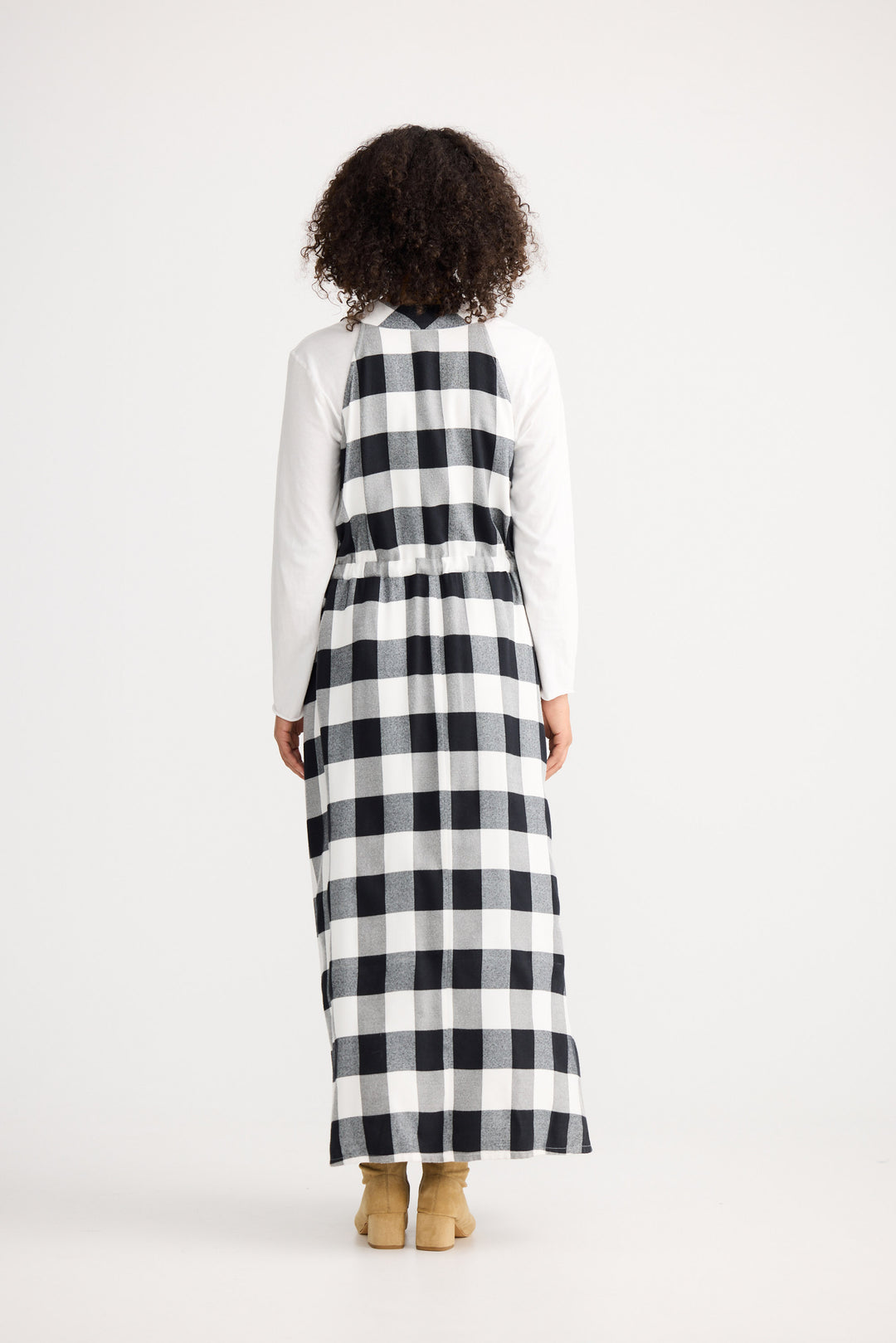 Person wearing a long black and white checkered dress with a white shirt underneath on a white background