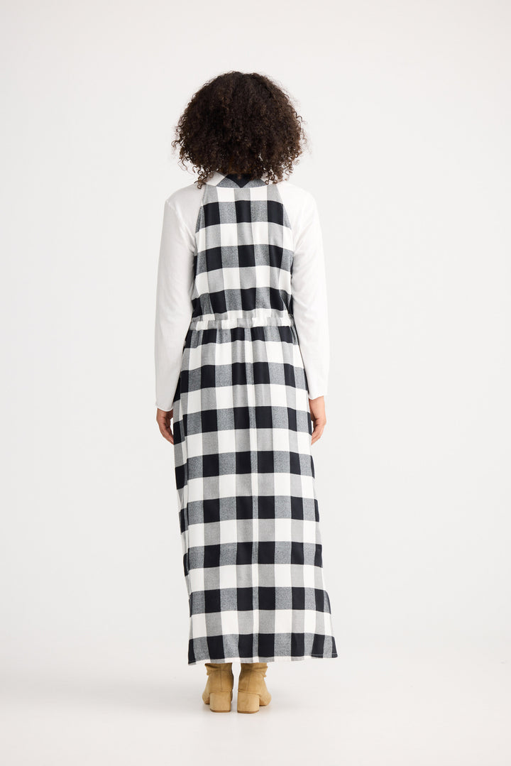 Person wearing a long black and white checkered dress with a white shirt underneath on a white background