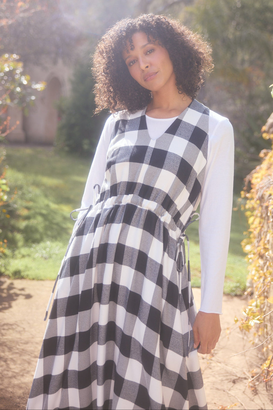Woman wearing a black and white checkered dress in a garden setting