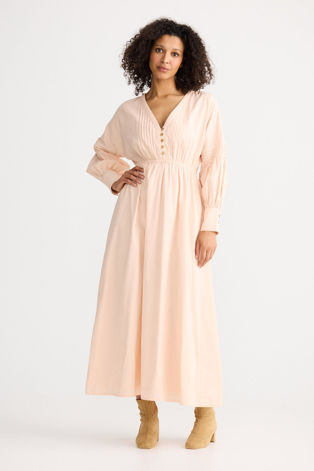 Woman wearing a long, light pink dress with a white background