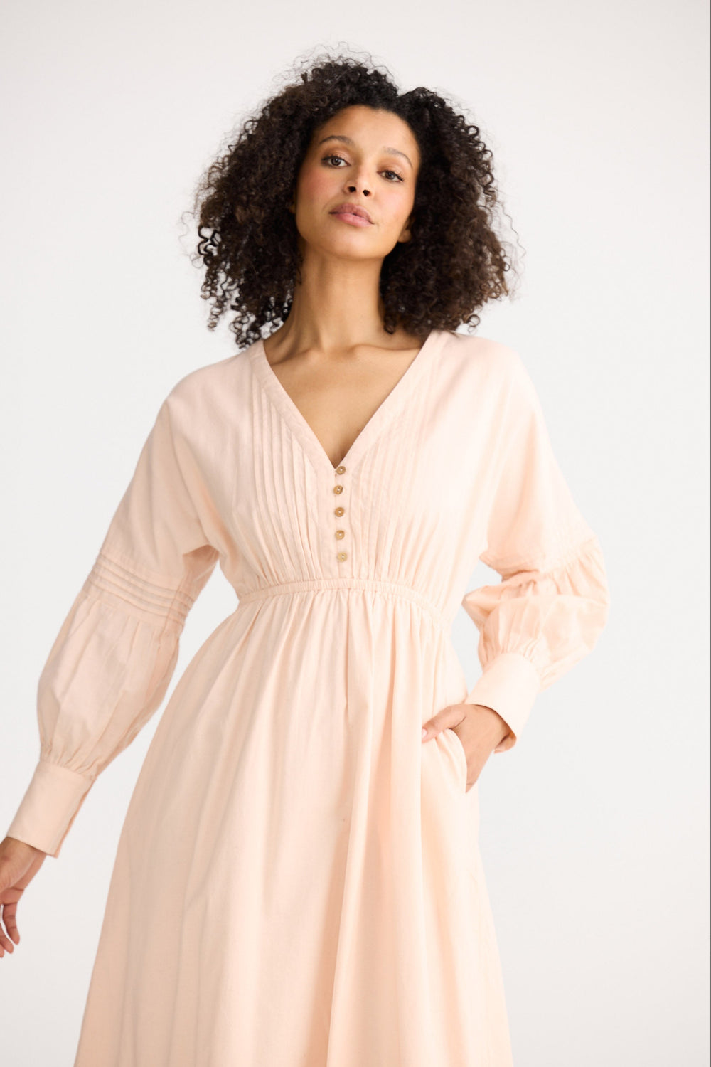 Woman wearing a light pink dress against a white background