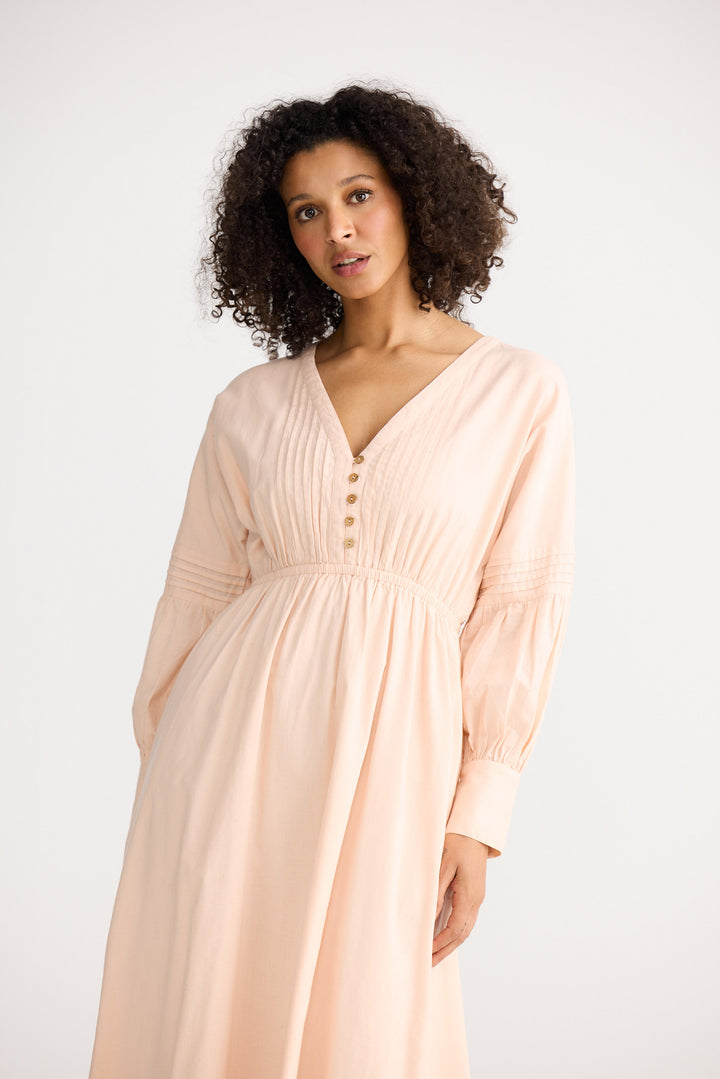 Woman wearing a light pink dress against a white background
