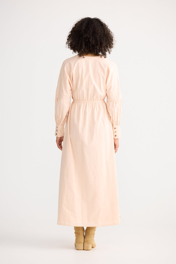 Person wearing a long beige coat on a white background