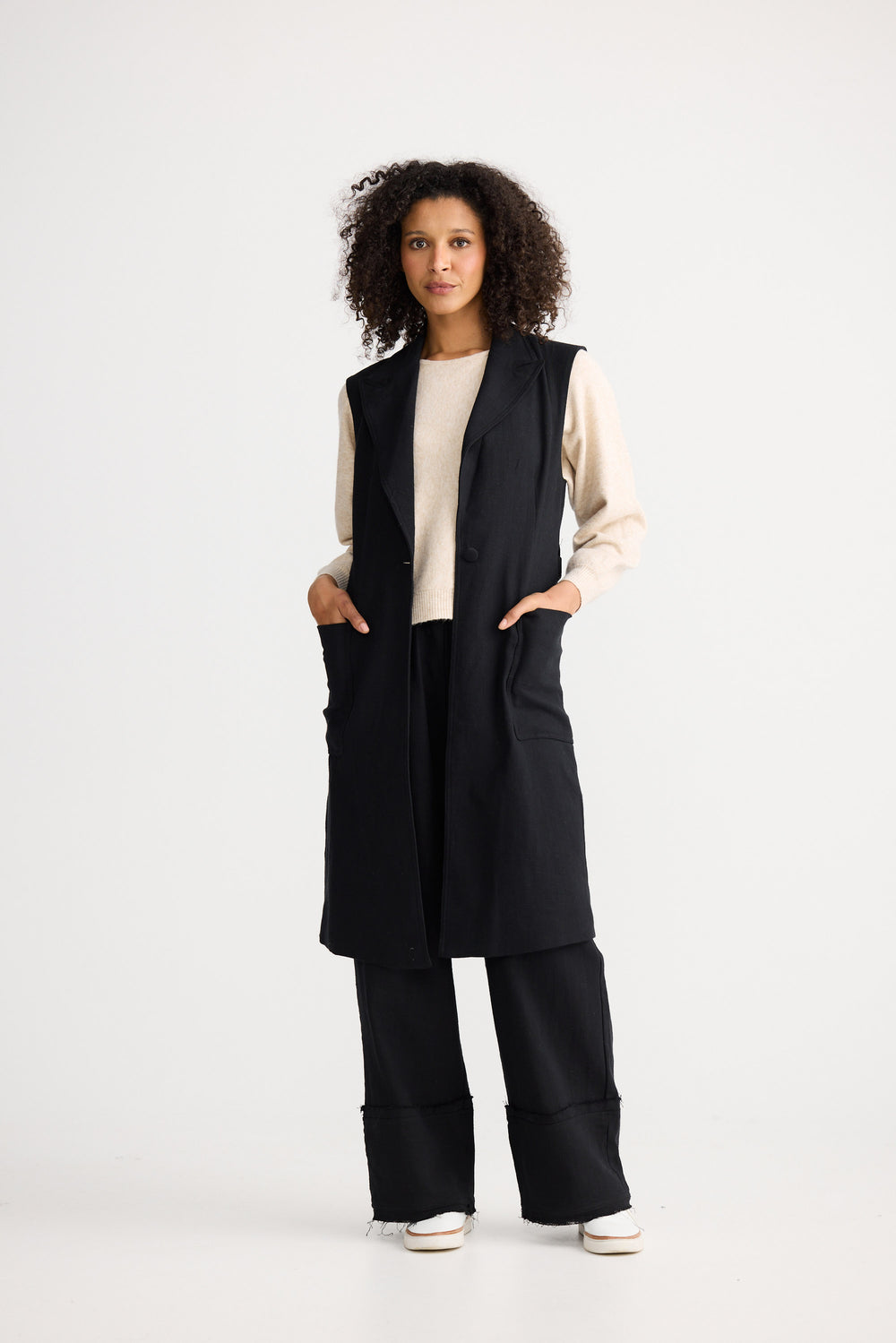 Model wearing black Noa Vest, side view on white background