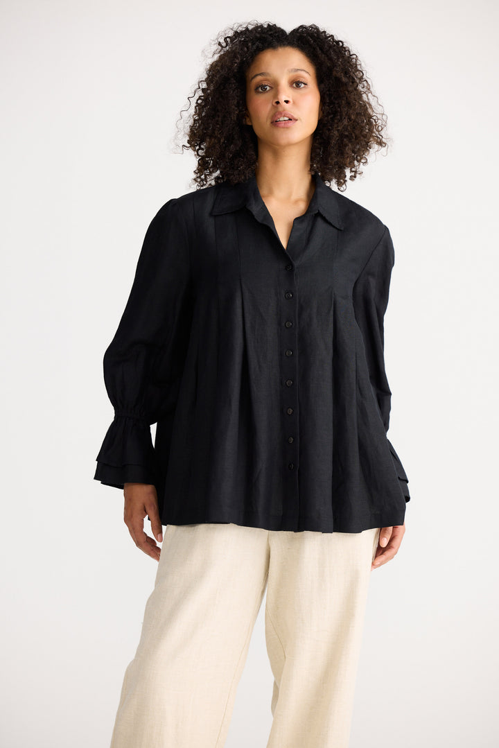 Woman wearing a black shirt and white pants on a white background