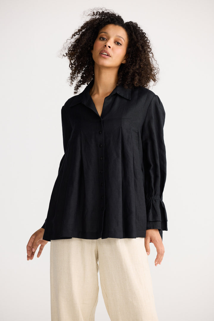 Woman wearing a black shirt and beige pants on a white background